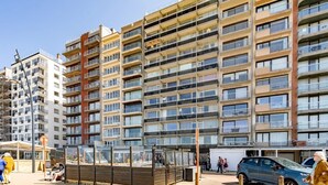Un edificio residencial de varios pisos con balcones, una zona de estar cubierta y una tienda DROOM.
