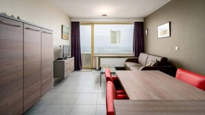 Una sala de estar moderna con una mesa de comedor, sofá y un ventanal con cortinas.