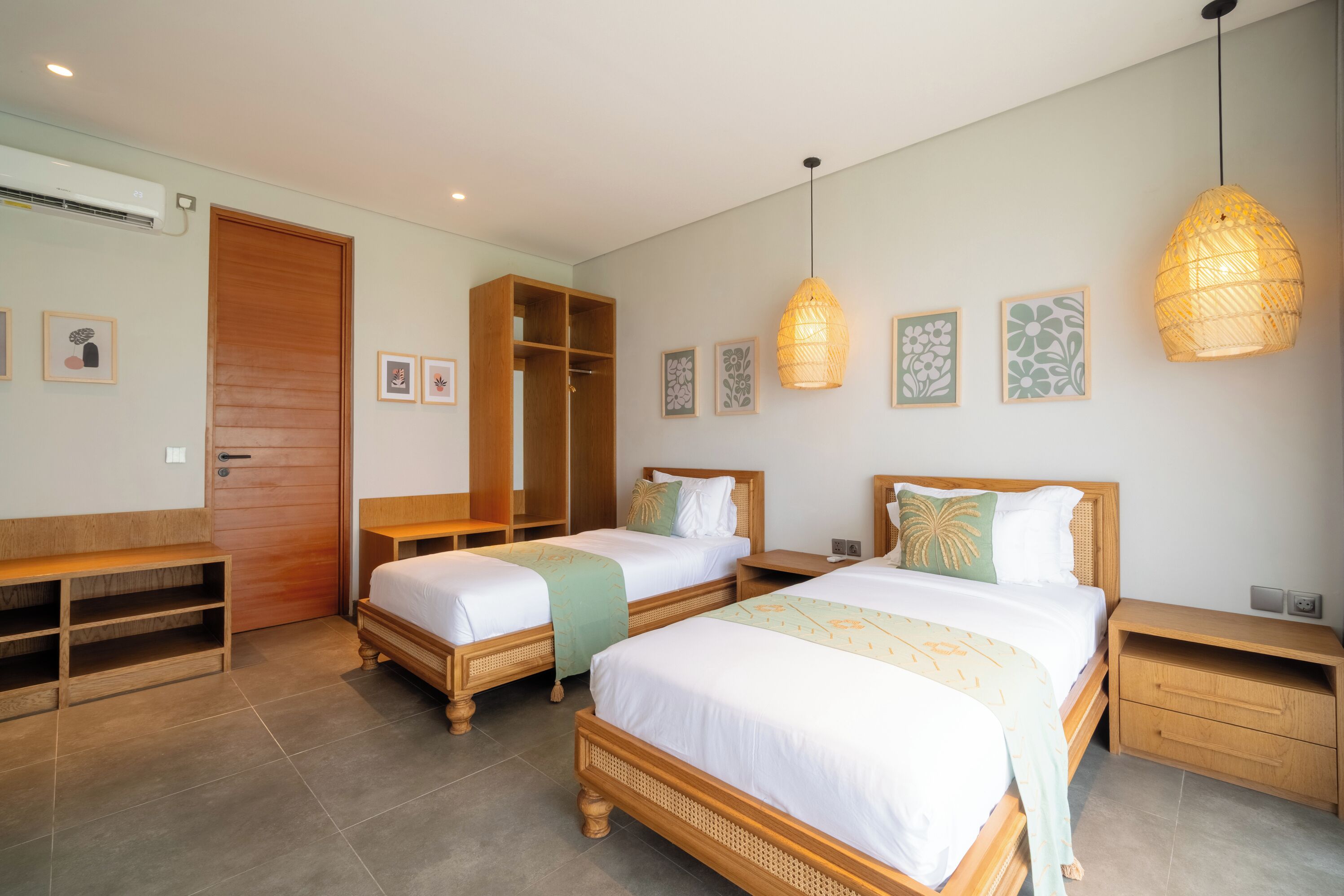 A hotel room with two beds, a wardrobe, a bench, and a bedside table.