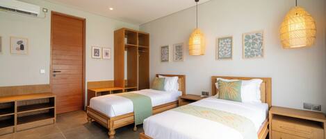 A hotel room with two beds, a wardrobe, a bench, and a bedside table.
