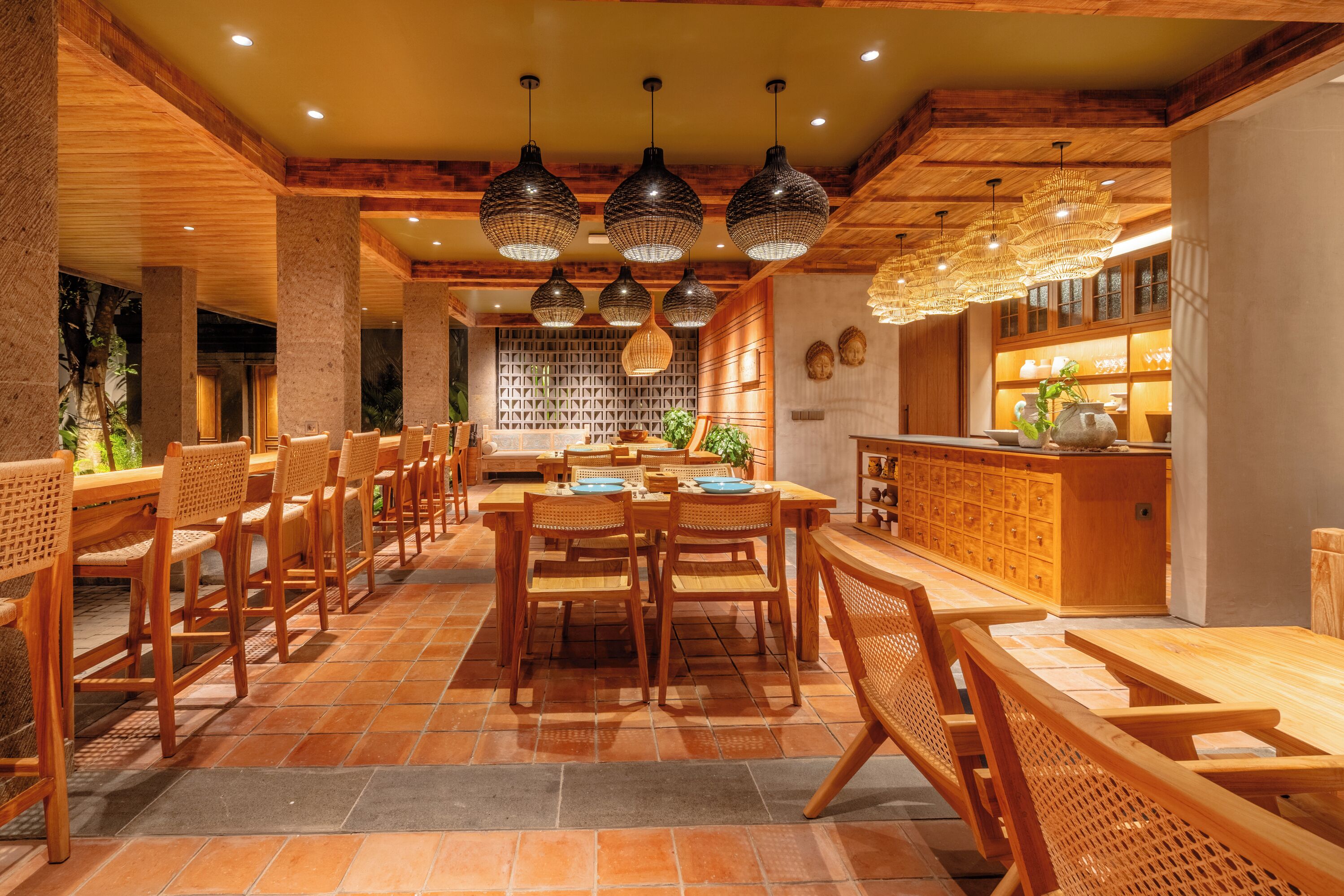A restaurant with wooden furniture, a tiled floor, and pendant lighting.