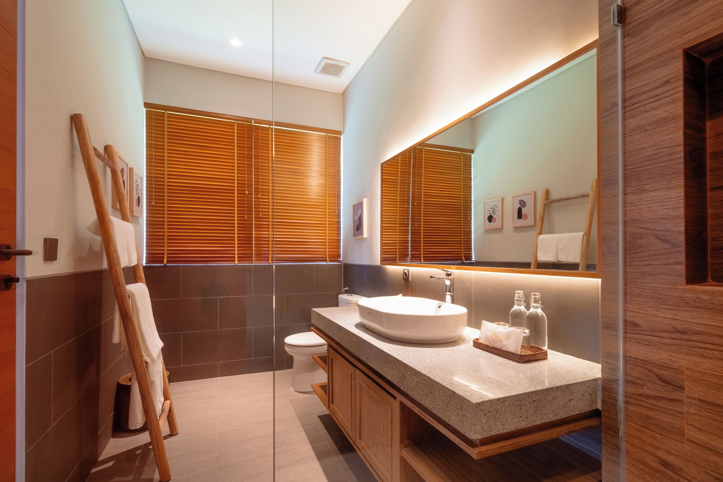 Une salle de bain moderne avec un grand miroir, des stores en bois, un lavabo et des toilettes.