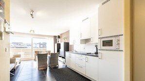 Een moderne keuken met witte kasten, een inbouwoven en een groot raam met uitzicht op een stadsbeeld.