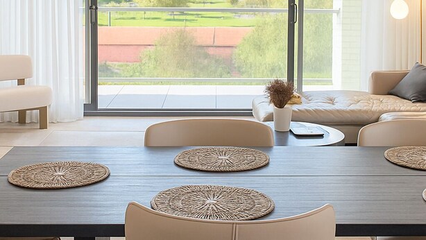 Un comedor moderno con vistas a la ciudad, un sofá y una mesa con individuales.