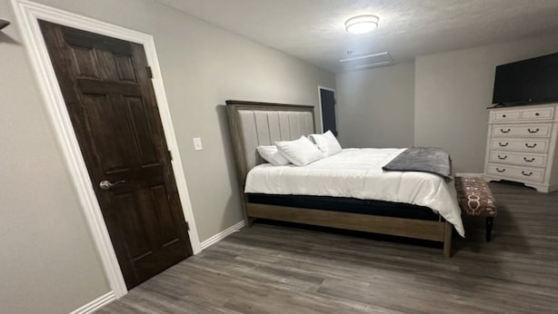 Een slaapkamer met een houten bed, een witte kapstok en een deur.