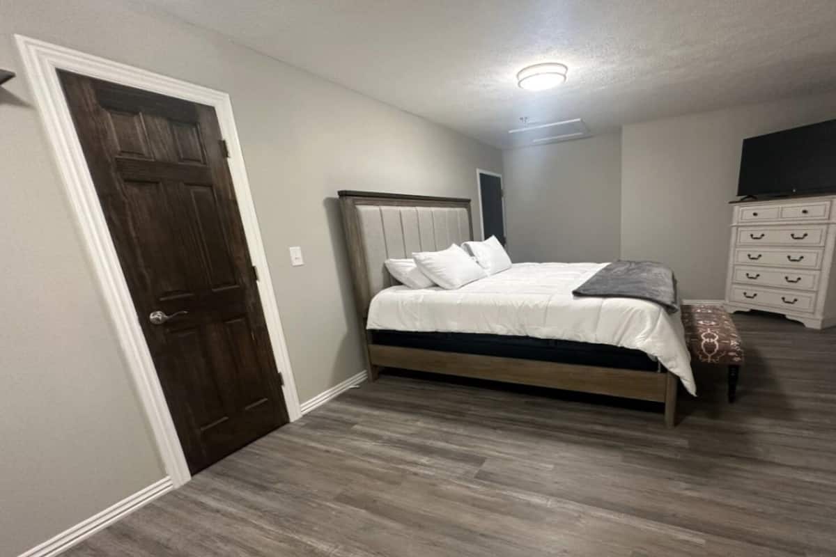 Een slaapkamer met een houten bed, een witte kapstok en een deur.