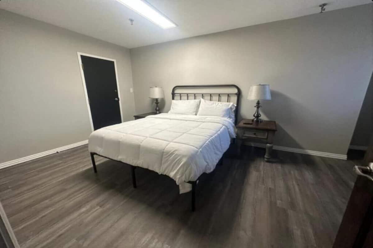 Een slaapkamer met een bed, twee nachtkastjes en een deur.