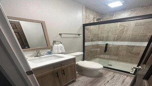 Een moderne badkamer met een douchecabine van glas, een wastafel met spiegel en een toilet.