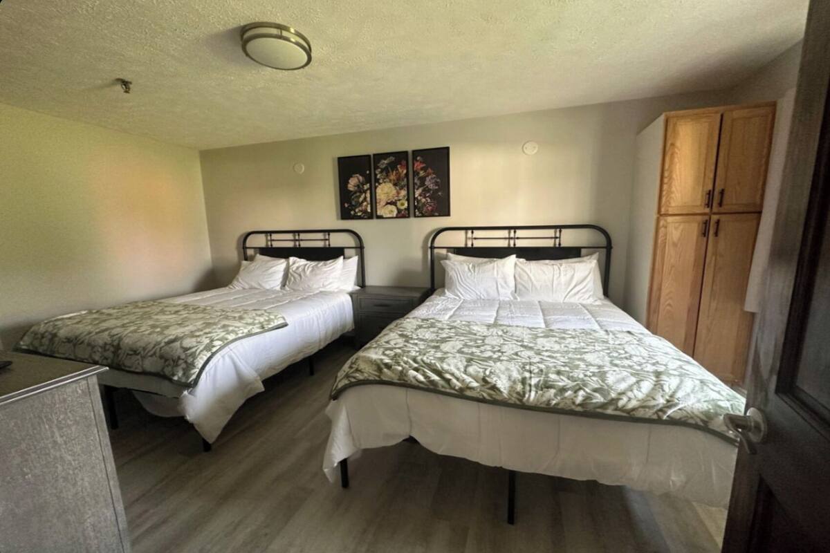 Een kamer met twee eenpersoonsbedden, een houten garderobe en een klein bureau.