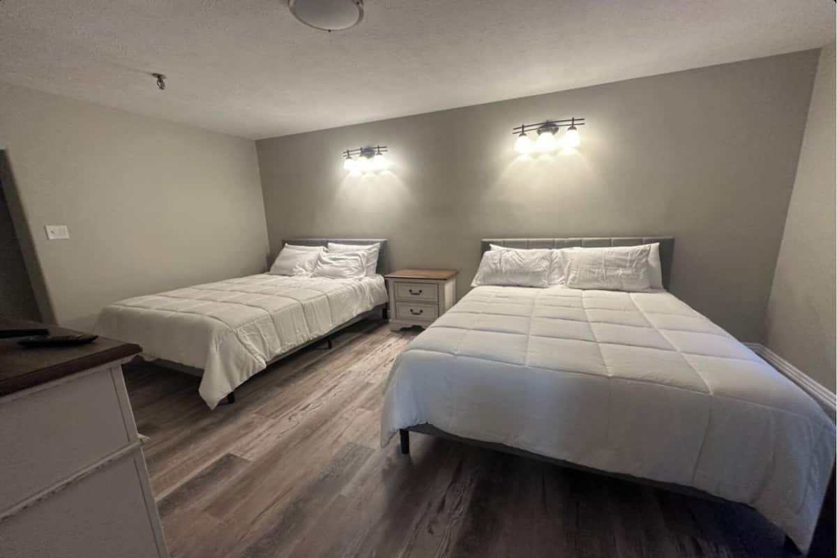 Een slaapkamer met twee bedden, een nachtkastje en een dressoir.