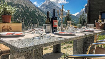 Une table dressée en plein air, avec une vue sur les montagnes, une bouteille de vin et un chandelier.