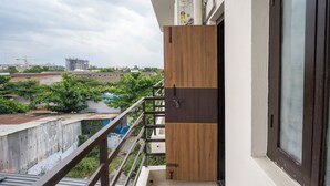 Un balcon donnant sur un chantier de construction et sur un espace verdoyant.