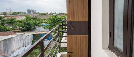 A balcony with a view of a construction site and greenery.