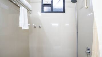 Eine moderne Dusche mit Handbrause, Fenster und Handtuchhalter.