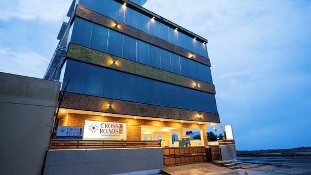 Un hôtel moderne doté d’une façade en verre, d’une enseigne indiquant « Cross Roads Boutique Hotel » et d’une entrée bien visible.