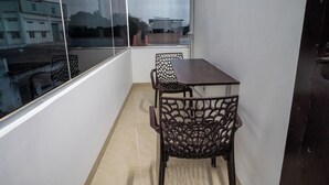 Un balcon avec une table et des chaises, une vue sur les immeubles et une porte.