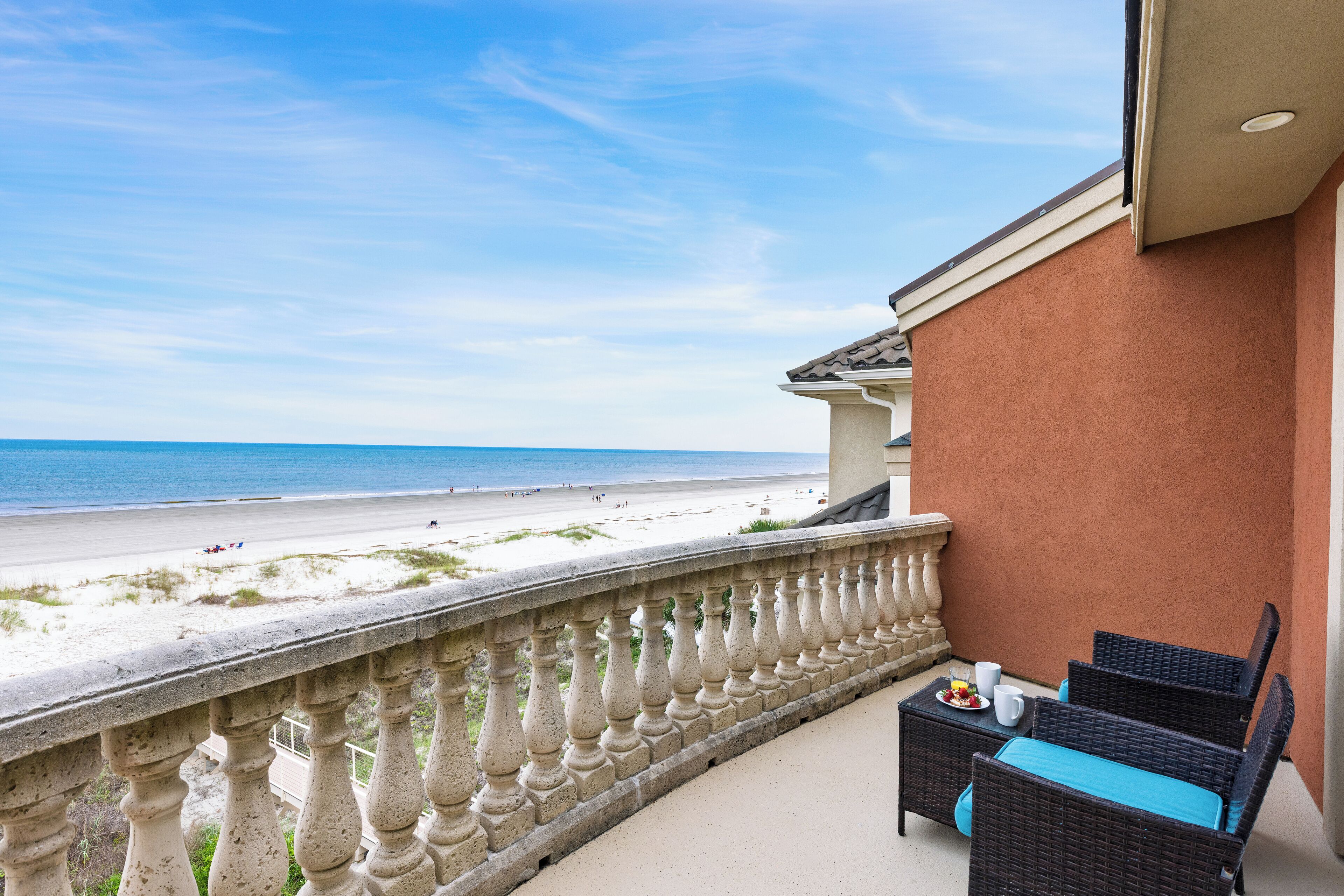 Un balcon doté de meubles en osier et offrant une vue sur la plage.