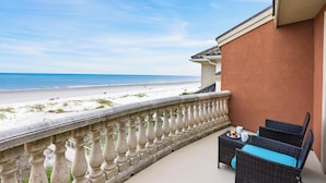 Un balcon doté de meubles en osier et offrant une vue sur la plage.