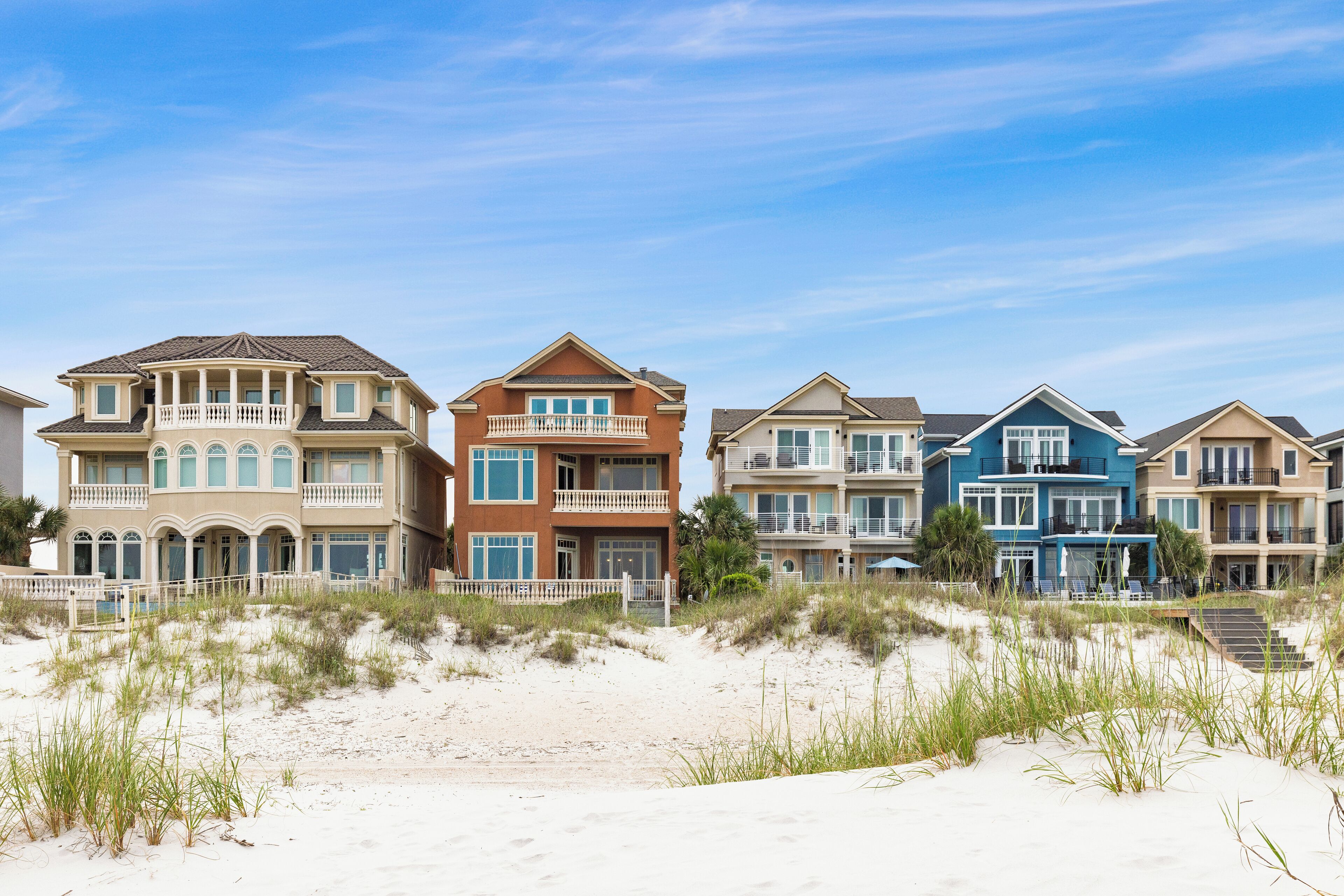 Une propriété située en bord de mer, avec des maisons à plusieurs étages dotées de balcons et de grandes fenêtres.
