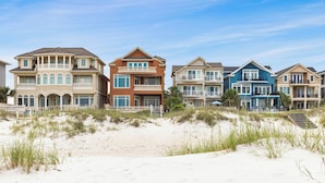 Une propriété située en bord de mer, avec des maisons à plusieurs étages dotées de balcons et de grandes fenêtres.