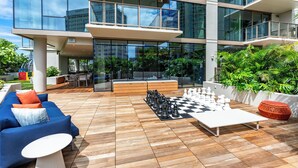 Un área de lounge al aire libre y de estilo moderno, con un tablero de ajedrez, asientos y vistas a la ciudad.