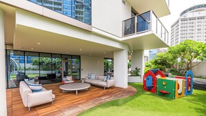 Un espacio moderno al aire libre con terraza de madera, una mesa redonda y un sofá.