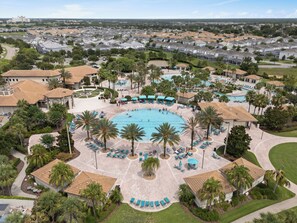 Vista aérea de un complejo turístico con una piscina central rodeada de palmeras y zonas de descanso.