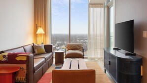 A modern living room with a sofa, armchair, and a television on a stand.
