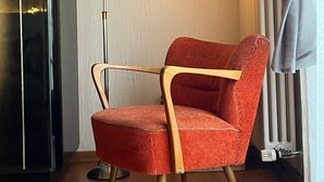 A room with a red upholstered chair, a black cabinet, a floor lamp, and a radiator. - Private Room 'Auf dem Karlsberg' with Wi-Fi (Weilburg)