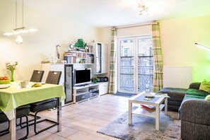 A living room with a dining area, a television, and a bookshelf.