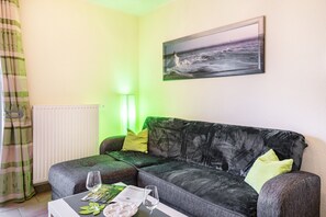 A living room with a sofa, a table with a glass, a lamp, and a framed picture on the wall.