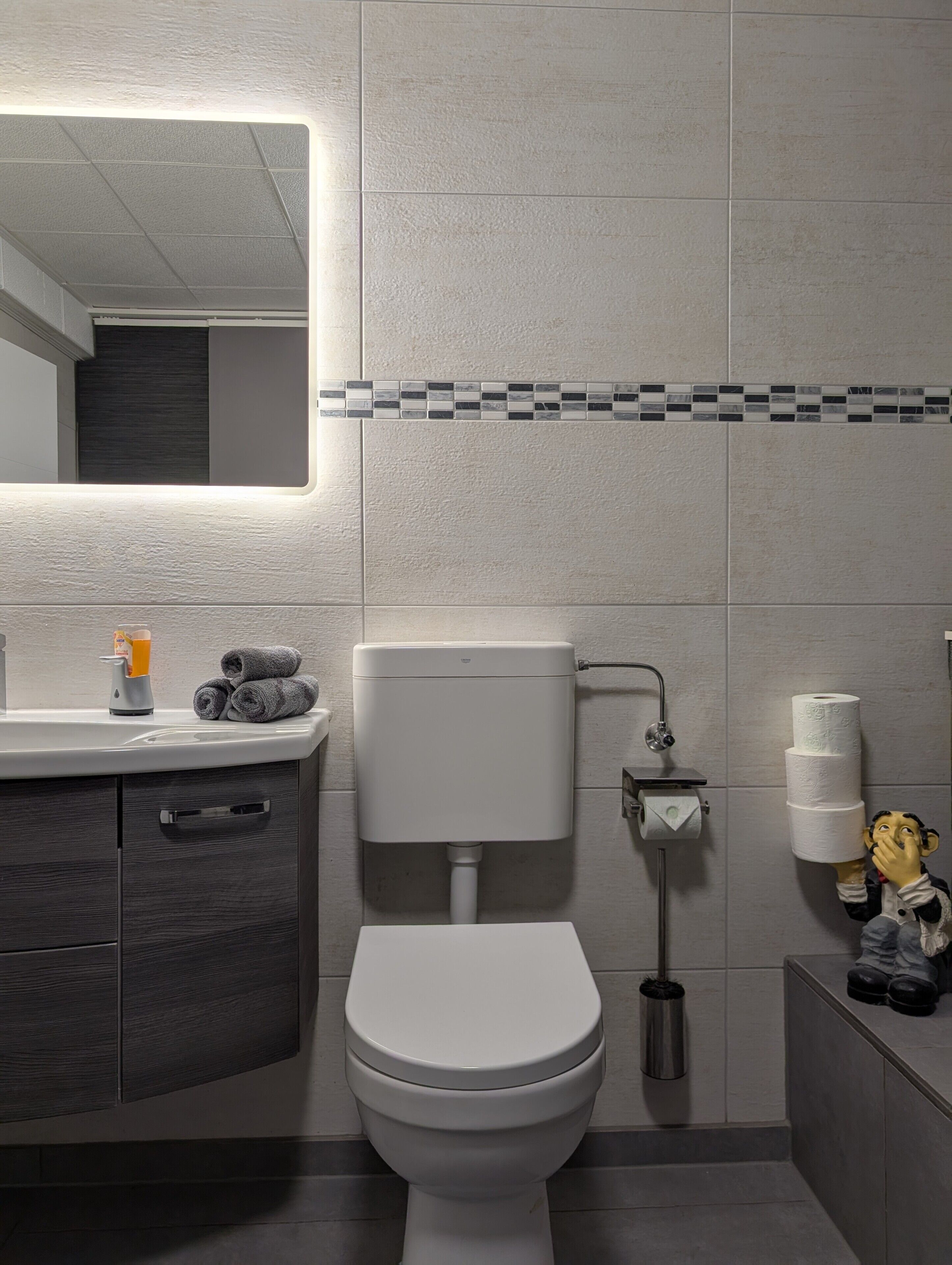 Un bagno moderno con un water, un lavandino e uno specchio.
