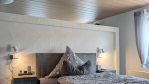 A bedroom with a bed, nightstands, a wall-mounted lamp, and a ceiling light. - Apartment 'An Der Quell' with Private Terrace, Private Garden and Wi-Fi (Blankenheim)