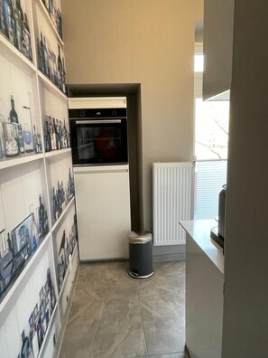 A compact kitchen with a built-in oven, a radiator, and a tiled floor.