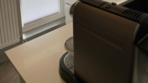 Una cocina moderna con microondas integrado, tostadora y ventana con persianas.