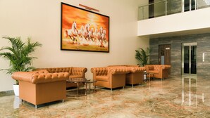 A lobby with leather sofas, a coffee table, and a large painting of horses.