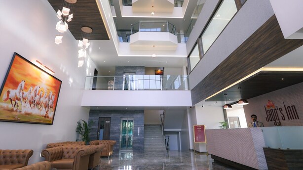 A modern hotel lobby with a high ceiling, multiple floors, a reception desk, and a large painting of horses.