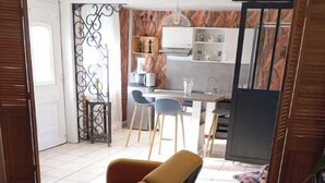 Une pièce comprenant un canapé, une table à manger avec des chaises, un coin cuisine et une porte coulissante.