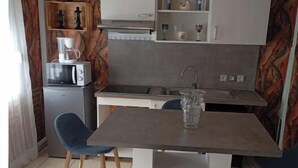 Une cuisine compacte dotée d’un îlot central, d’un four à micro-ondes, d’un évier et d’un petit réfrigérateur.