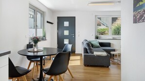 A modern living space with a dining area, a sofa, and a view of the outdoors. - Apartment 'Seeglück' with Mountain View, Private Terrace and Wi-Fi (Bodman-Ludwigshafen)