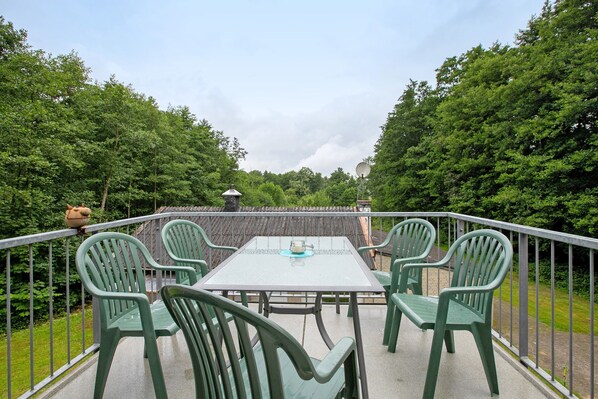 Un balcon agrémenté d’une table et de chaises, entouré de verdure.