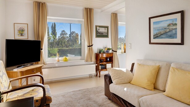 A living room with a television, sofa, and a window with curtains.