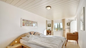 A bedroom with a large bed, bedside table, lamp, and a chair.