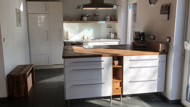 Eine moderne Küche mit weißen Schränken, einer Holz Arbeitsplatte und einem eingebauten Ofen.