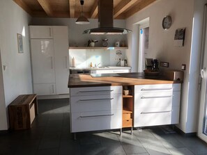 Une cuisine moderne avec des meubles blancs, un plan de travail en bois et un four encastré.