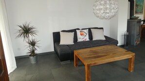Ein Wohnzimmer mit einer Couch, einem Couchtisch, einer Zimmerpflanze und einer dekorativen Leuchte.