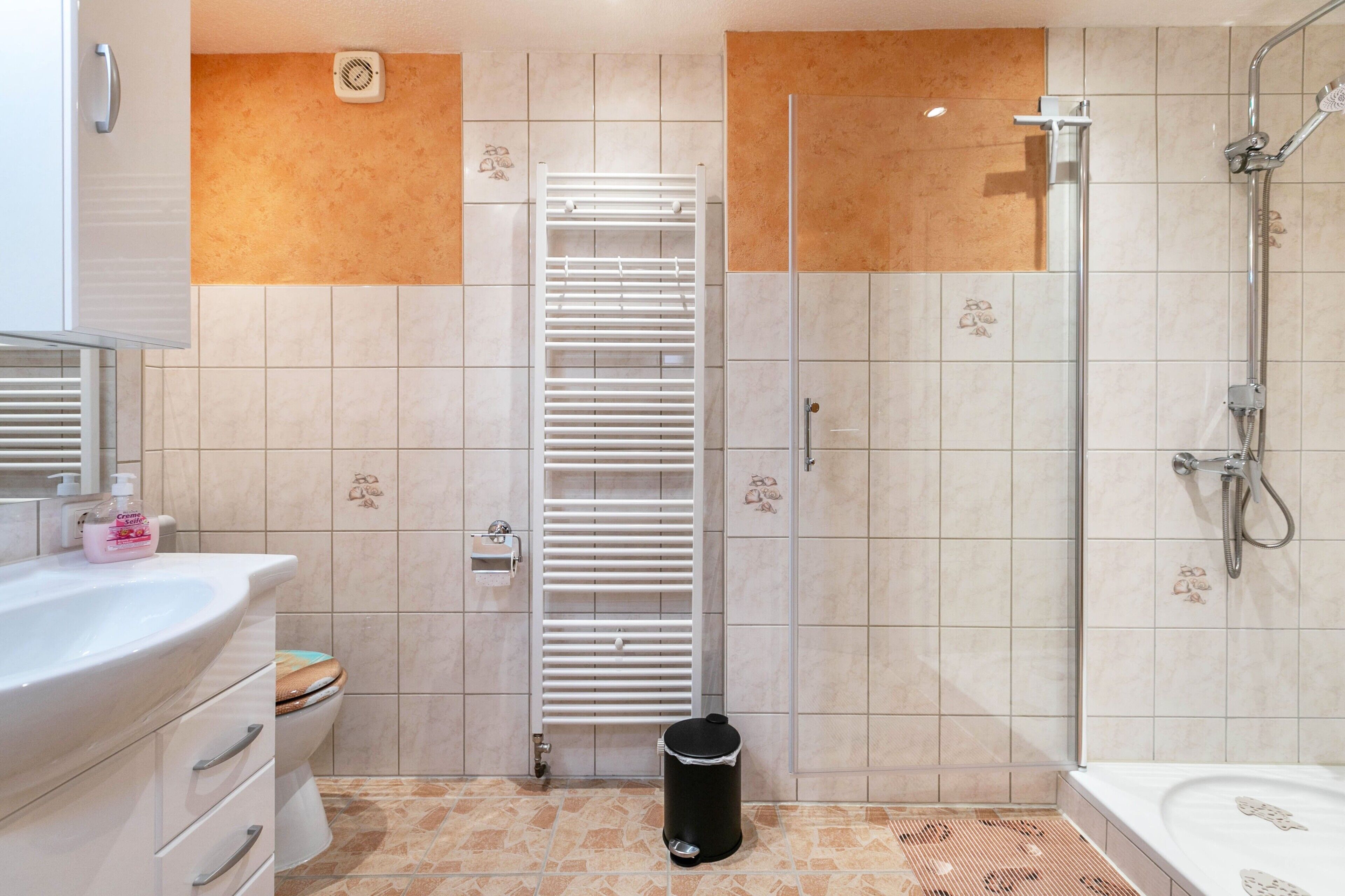 A bathroom with a toilet, sink, shower, and a towel rack.