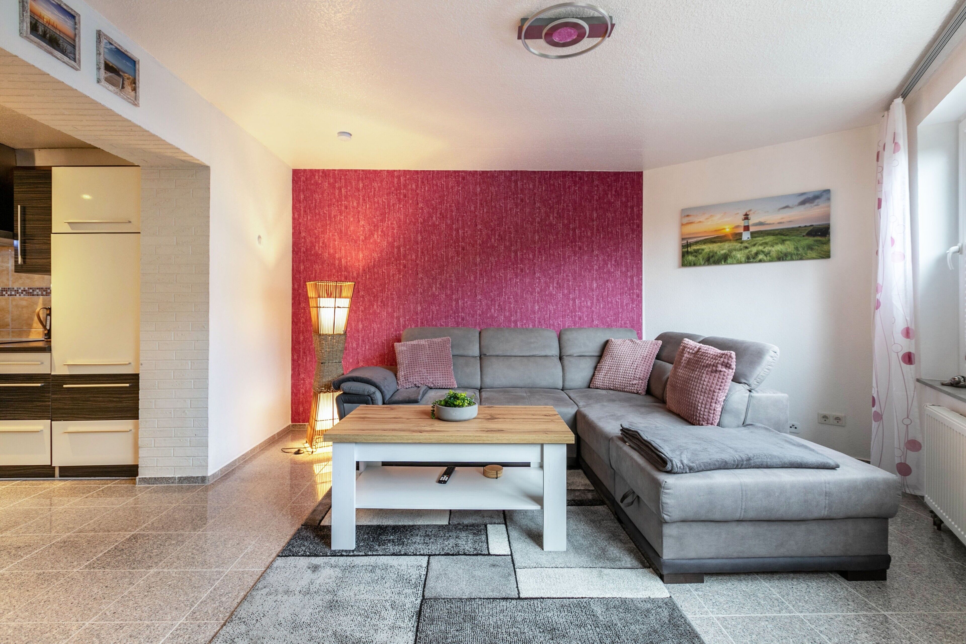 A modern living room with a sofa, a coffee table, and a red accent wall.