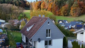 Une maison d’habitation avec un toit en pente, une antenne parabolique et des panneaux solaires.