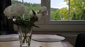 Une table à manger ornée d’un vase de fleurs blanches, d’une assiette et d’un set de table.